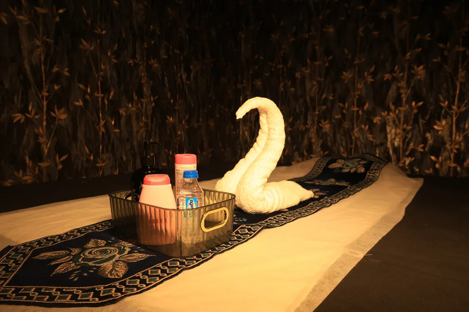 Massage bed at Anantram Spa with a folded towel swan, embroidered runner and a basket of massage oils under warm golden light
