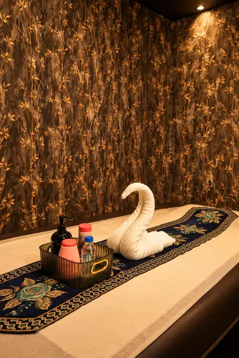 Massage bed with towel swan in a gold-lit therapy room at Anantram Spa